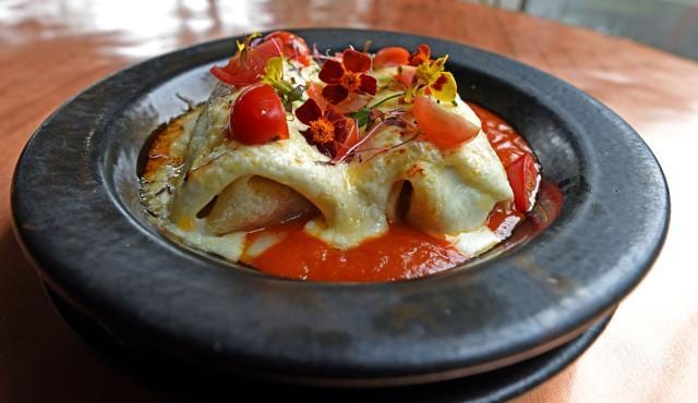 Gooey and delicious, Mexican Enchiladas at LIMA with a sprinkling of fresh chopped tomatoes and edible flowers for garnish. (Satyabrata Tripathy / HT Photo)