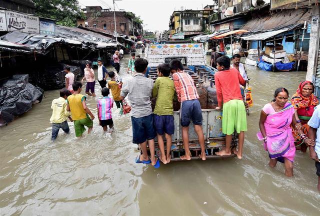 People wade through a flooded street after high tide in river Ganga in Kolkata on Monday. (PTI) People wade through a flooded street after high tide in river Ganga in Kolkata on Monday. (PTI)