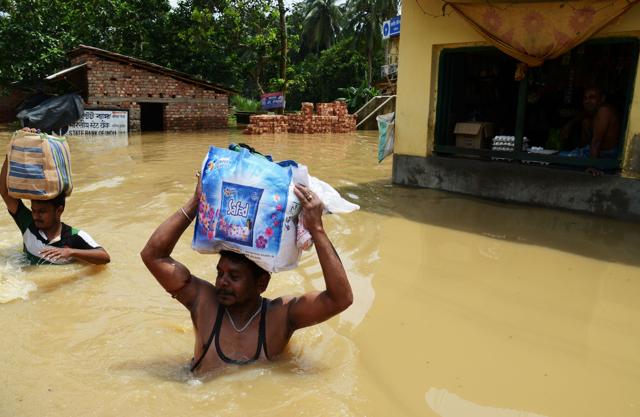 Flood victims wade through water after collecting relief materials in Amta area of Howrah district in West Bengal. (AFP)