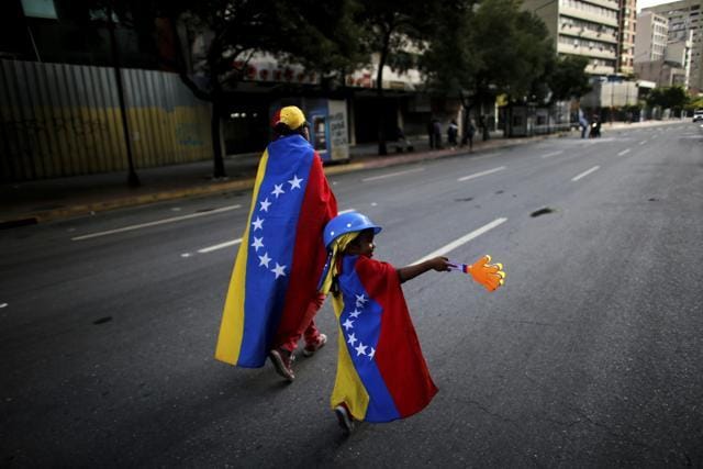 An anti-government demonstrator and her daughter wrapped in the Venezuelan flag walk on an empty street in Caracas, Venezuela. (AP Photo) An anti-government demonstrator and her daughter wrapped in the Venezuelan flag walk on an empty street in Caracas, Venezuela. (AP Photo)