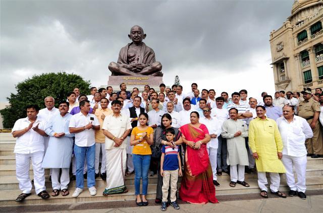 Gujarat Congress MLAs and Karnataka energy minister D K Shivakumar stage a protest in front of the statue of Mahatama Gandhi at Karnataka assembly in Bengaluru on Saturday. (PTI) Gujarat Congress MLAs and Karnataka energy minister D K Shivakumar stage a protest in front of the statue of Mahatama Gandhi at Karnataka assembly in Bengaluru on Saturday. (PTI)