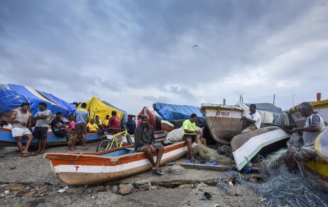 Fishermen rest after a day spent checking their boats for leaks and plugging them. (Kunal Patil/HT ) Fishermen rest after a day spent checking their boats for leaks and plugging them. (Kunal Patil/HT )