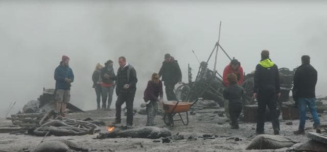 Crew members covering props in fake ash.