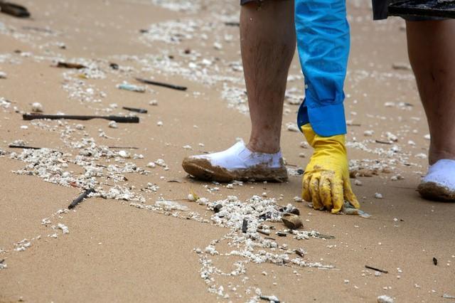 A volunteer collects crystallised palm oil. (Reuters Photo) A volunteer collects crystallised palm oil. (Reuters Photo)