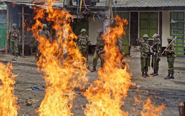 Riot police prepare to advance towards protesters past burning barricades. (AP Photo)