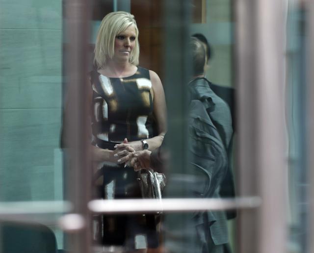 Shannon Melcher, former girlfriend of a Denver radio host who allegedly groped pop singer Taylor Swift, is helped to avoid the media after testifying in the civil trial in federal court. (AP)