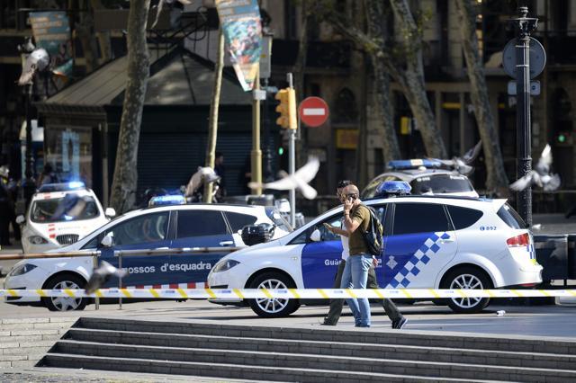 Plain-clothes policemen phone as they walk past police cars in a cordoned off area after a van ploughed into the crowd, injuring several persons on the Rambla in Barcelona on August 17, 2017. (AFP) Plain-clothes policemen phone as they walk past police cars in a cordoned off area after a van ploughed into the crowd, injuring several persons on the Rambla in Barcelona on August 17, 2017. (AFP)