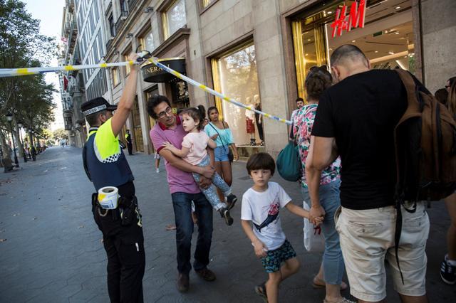 A police officer helps evacuate people after a van crashed into pedestrians near the Las Ramblas avenue in central Barcelona, Spain August 17, 2017. (REUTERS) A police officer helps evacuate people after a van crashed into pedestrians near the Las Ramblas avenue in central Barcelona, Spain August 17, 2017. (REUTERS)