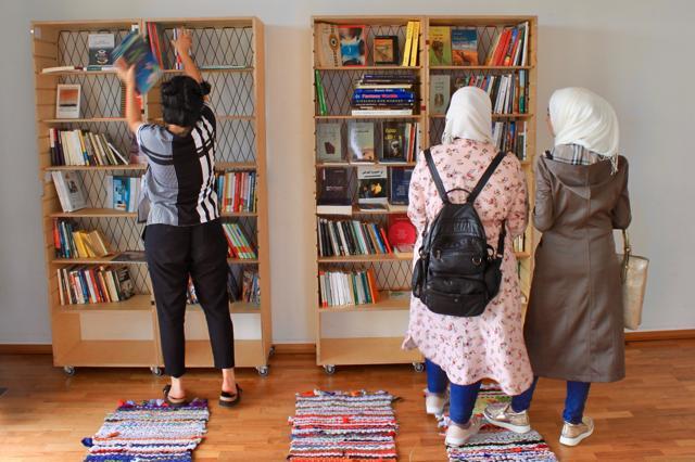 In this July 31, 2017 photo two women look at books while a volunteer, left, organizes books at the 'Baynetna' cultural centre library in Berlin. The newly opened centre was founded by migrants to promote Arab literature and culture. (AP) In this July 31, 2017 photo two women look at books while a volunteer, left, organizes books at the 'Baynetna' cultural centre library in Berlin. The newly opened centre was founded by migrants to promote Arab literature and culture. (AP)