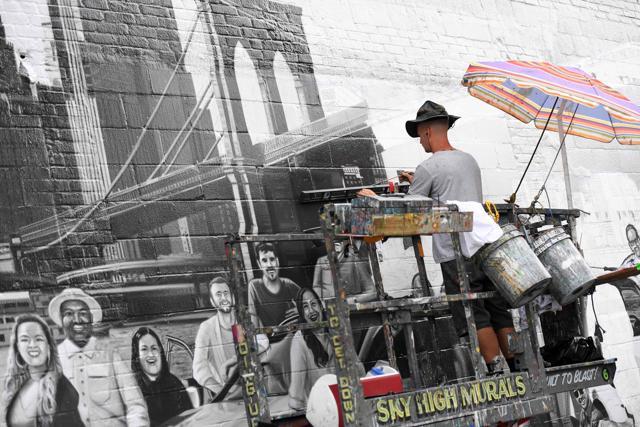 Liam Williams, a painter for Colossal Media, paints an ad on the side of Colossal Media's office building (AFP) Liam Williams, a painter for Colossal Media, paints an ad on the side of Colossal Media's office building (AFP)