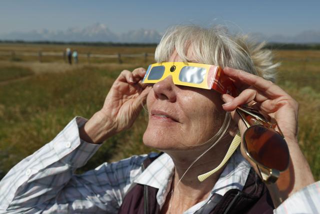Penny Farster-Narlesky of Denver Colorado test her solar eclipse glasses at an roadside information center in Grand Teton National Park on August 20, 2017 outside Jackson, Wyoming. People are flocking to the Jackson and Teton National Park area for the 2017 solar eclipse which will be one of the areas that will experience a 100% eclipse on Monday August 21, 2017. (AFP)