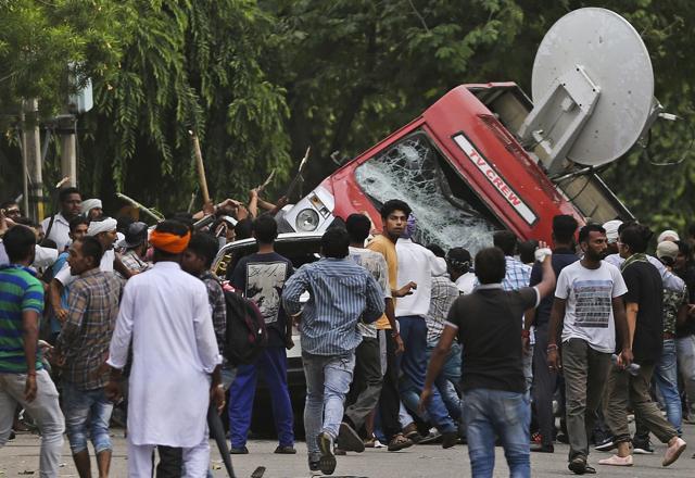 Dera Sacha Sauda sect members overturn an OB van on the streets of Panchkula (AP) Dera Sacha Sauda sect members overturn an OB van on the streets of Panchkula (AP)