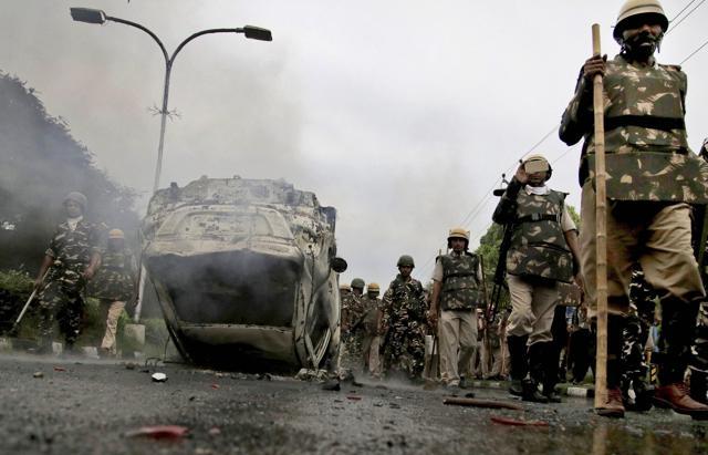 Security personnel walk past a vehicle set afire in violence following Dera Sacha Sauda chief Gurmeet Ram Rahim’s conviction in Panchkula. (PTI Photo) Security personnel walk past a vehicle set afire in violence following Dera Sacha Sauda chief Gurmeet Ram Rahim’s conviction in Panchkula. (PTI Photo)