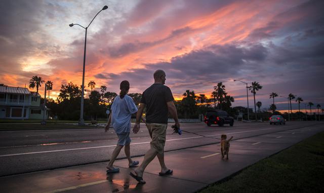 A couple walks their dog along Ocean Drive in Corpus Christi, Texas, on Saturday. Hurricane Harvey hit the Texas coast late Friday as a Category 4 storm, damaging buildings and leaving tens of thousands without power. (AP Photo)