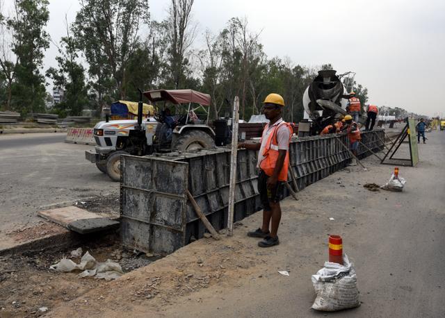 Labourers work amid busy traffic. (Sonu Mehta/HT PHOTO) Labourers work amid busy traffic. (Sonu Mehta/HT PHOTO)