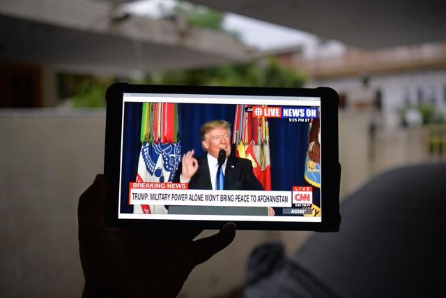 A Pakistani resident watches his tablet device in Islamabad on August 22, 2017, showing a live broadcast of US President Donald Trump delivering his address from Joint Base Myer-Henderson Hall in Arlington, Virginia in the US. (AFP)