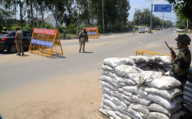 Personnel of para-military forces stand guard at an entry point of Rohtak on Sunday. (PTI) Personnel of para-military forces stand guard at an entry point of Rohtak on Sunday. (PTI)