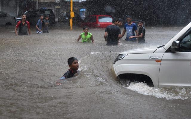 People make their way through a flooded street in Mumbai on Tuesday. (PTI Photo) People make their way through a flooded street in Mumbai on Tuesday. (PTI Photo)