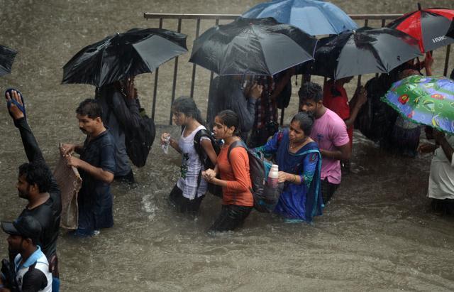 People walk along a flooded street in Mumbai during a heavy downpour on Tuesday. (AFP)