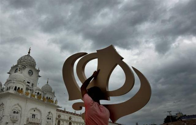 A worker carries the Sikh religious emblem 'Khanda' at the Golden Temple in the backdrop of a rainy day in Amritsar on Tuesday. (PTI) A worker carries the Sikh religious emblem 'Khanda' at the Golden Temple in the backdrop of a rainy day in Amritsar on Tuesday. (PTI)