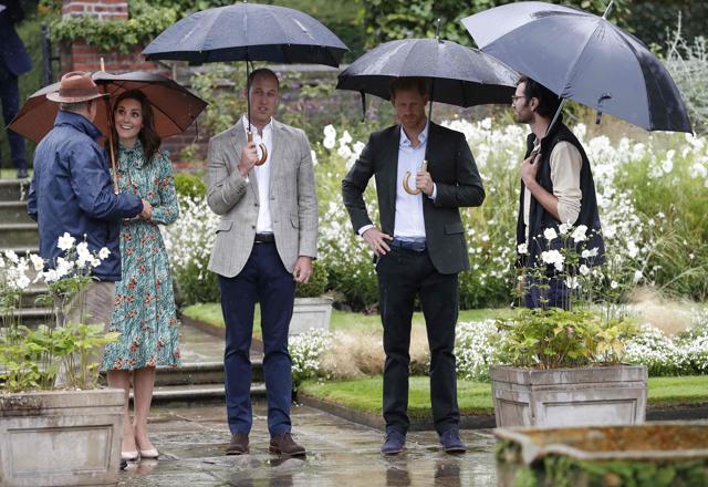 Britain's Prince William, Duke of Cambridge (3L), his wife Britain's Catherine, Duchess of Cambridge (2L) and his brother Britain's Prince Harry (2R), talk with head gardener Sean Harkin (R), during an event at the memorial gardens in Kensington Palace. (AFP)