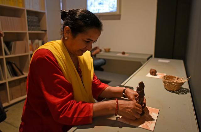Marketing executive Hiral Sampat turns a clay mound into a tree, to be added to the installation. (Satyabrata Tripathy / HT Photo)