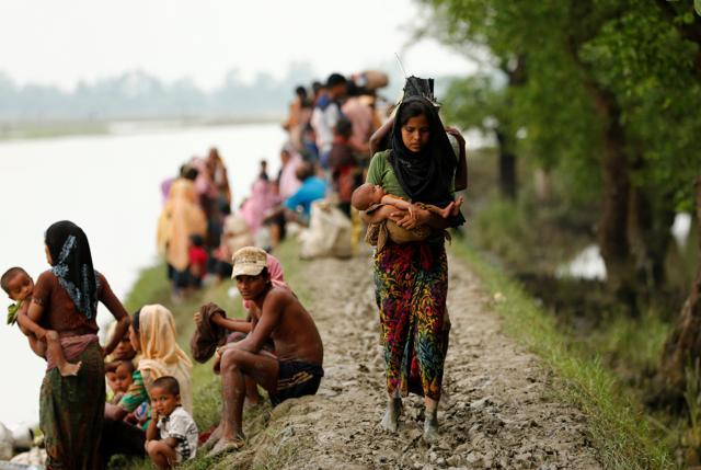 A Rohingya refugee woman with her child walks on the muddy path after crossing the Bangladesh-Myanmar border in Teknaf, Bangladesh on September 7. (REUTERS)