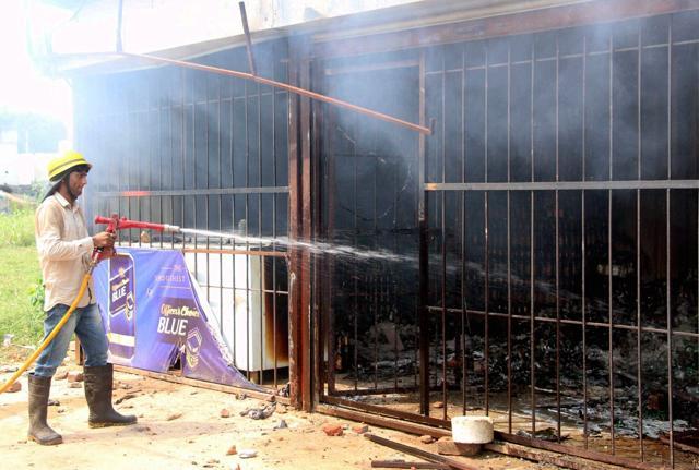 A firefighter tries to control a blaze at a liquor shop set afire by protesters on Sunday. (PTI) A firefighter tries to control a blaze at a liquor shop set afire by protesters on Sunday. (PTI)