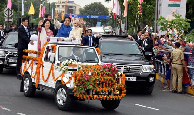Prime Minister Narendra Modi, Japanese premier Shinzo Abe and his wife, Akie Abe, wave from an open vehicle during their roadshow in Ahmedabad on Wednesday. (PTI photo)