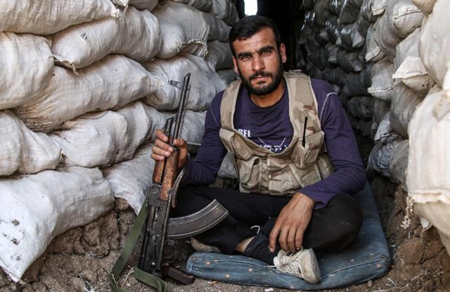 A Syrian rebel fighter poses for a picture with a Kalashnikov assault rifle while sitting in a fortified position in the central Syrian rebel-held town of Talbiseh, north of Homs, on August 3, 2017. (AFP)