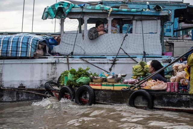 A boat vendor offers her vegetables to a house boat resident. (Roberto Schmidt/AFP) A boat vendor offers her vegetables to a house boat resident. (Roberto Schmidt/AFP)