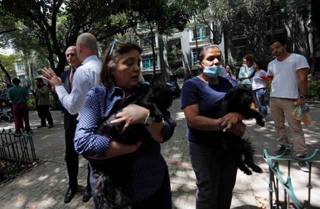 Women carrying their dogs stand outside their homes. After the screams and the shock, people quickly set to work digging for survivors. (REUTERS) Women carrying their dogs stand outside their homes. After the screams and the shock, people quickly set to work digging for survivors. (REUTERS)