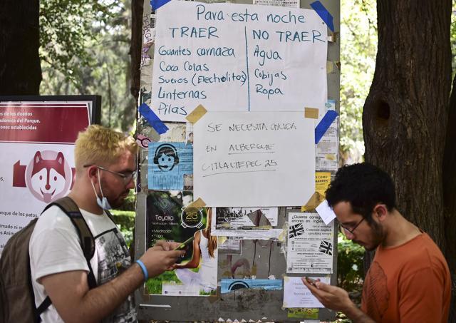 Posters on a board inform about items needed by the rescuers taking part in the cleanup of rubble from collapsed buildings in search of survivors. (AFP)