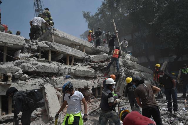 Rescuers and volunteers search for survivors amid the rubble of a multistory building flattened by the quake. (AFP)