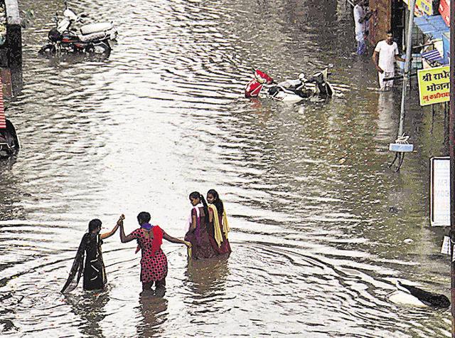 Commuters wade through a waterlogged road outside Nallasopara station on Wednesday. (Pramod Thakur/HT PHOTO)