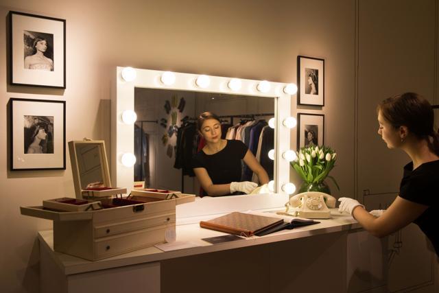 An employee poses at a dressing table displaying a jewellery box, circa 1970, with a reserve price of £1,000 - £1,500 (L) and a Swiss white-plastic rotary dial telephone by Autophon, 1960s, with a reserve price of £400 - £600 during a preview of Audrey Hepburn’s personal collection at Christie’s auction house. (AFP/Daniel Leal-Olivas)