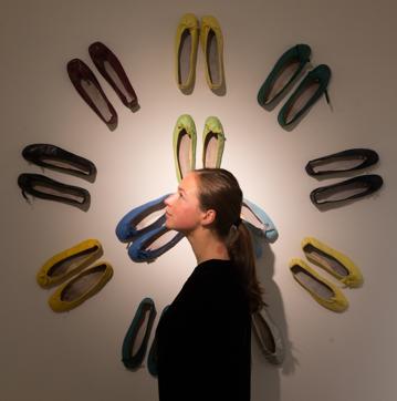 An employee poses in front of an installation displaying pairs of leather ballet pumps during the preview. (AFP/Daniel Leal-Olivas)