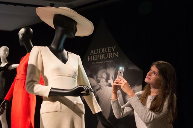 An employee poses alongside a display of outfits during a preview of Audrey Hepburn's personal collection. (AFP/Daniel Leal-Olivas)