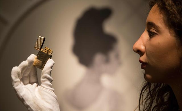 An employee holds the My Fair Lady, 1964/Gene Allen cigarette lighter with a reserve price of £3,000 - £5,000. (AFP/Daniel Leal-Olivas)