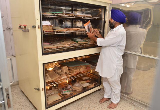 An SGPC employee keeping rare manuscripts and old books in a fumigation chamber at the Sikh Reference Library. (Sameer Sehgal/HT) An SGPC employee keeping rare manuscripts and old books in a fumigation chamber at the Sikh Reference Library. (Sameer Sehgal/HT)