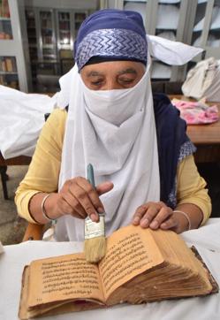 An employee cleaning a rare book for preservation at Sikh Reference Library in the Golden Temple complex on Sunday, September 24. (Sameer Sehgal/HT) An employee cleaning a rare book for preservation at Sikh Reference Library in the Golden Temple complex on Sunday, September 24. (Sameer Sehgal/HT)