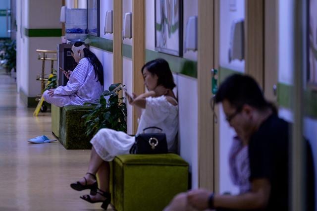 In this photograph taken on August 22, 2017, a young woman (left) with a bandaged face sits inside Huamei Medical Cosmetology Hospital in Shanghai. Plastic surgery is booming in China. (AFP) In this photograph taken on August 22, 2017, a young woman (left) with a bandaged face sits inside Huamei Medical Cosmetology Hospital in Shanghai. Plastic surgery is booming in China. (AFP)