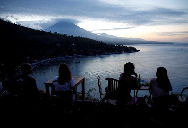 Tourists have a drink while watching the sunset behind Mount Agung, a volcano on the highest alert level, in Amed on the resort island of Bali, Indonesia September 25, 2017. (Reuters )