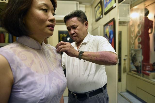 "Qipao" maker Chen Chung-hsin (R) adjusting a "qipao" on a customer at his studio in Taipei. (AFP) "Qipao" maker Chen Chung-hsin (R) adjusting a "qipao" on a customer at his studio in Taipei. (AFP)