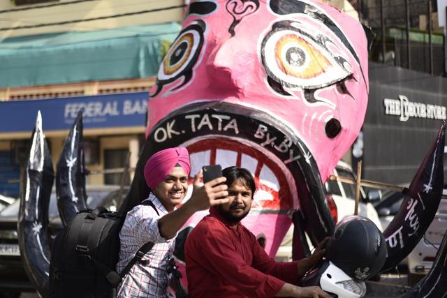 Passersby pose to take a picture with a giant effigy head near Tagore Garden Metro Station, in New Delhi. (Burhaan Kinu/HT PHOTO)