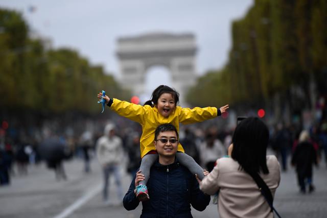 A family posses for a photograph along the Champs Elysees with the Arc de Triumph as a backdrop. (AFP Photo) A family posses for a photograph along the Champs Elysees with the Arc de Triumph as a backdrop. (AFP Photo)