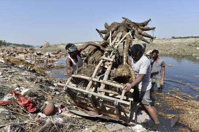 Workers from flood control department remove idols from the riverbed. (Sanchit Khanna/HT PHOTO)