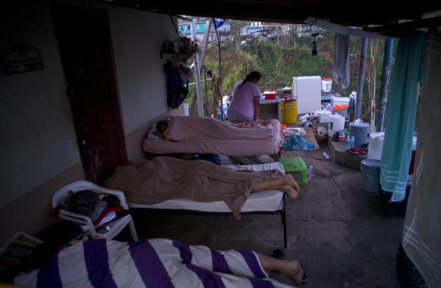 Julia Rivera gets up from the makeshift bed in the porch of her house as her children sleep, in Moravis, Puerto Rico, Sunday, Oct. 1, 2017. According to Rivera on the night of the hurricane they took shelter in another home and when they came back they saw that their house was destroyed by Hurricane Maria. She is expecting help from the government or they will leave Puerto Rico for anther place, she says. (AP)