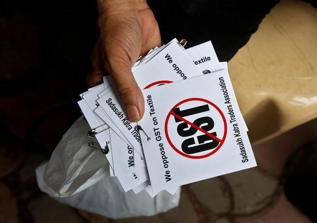 A cloth merchant holds message papers to distribute as he attends a procession during a strike to protest the implementation of the Goods and Services Tax (GST) on textiles in Kolkata. (Reuters File Photo) A cloth merchant holds message papers to distribute as he attends a procession during a strike to protest the implementation of the Goods and Services Tax (GST) on textiles in Kolkata. (Reuters File Photo)