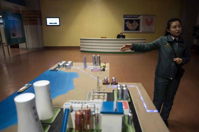 A guide standing before a model of a power station at the Sci-Tech complex in Pyongyang on November 26, 2016. (AFP File )